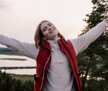 Woman enjoying freedom in a scenic landscape with open arms.